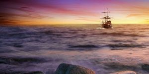 Barco de madera con dos mástiles en el mar al atardecer